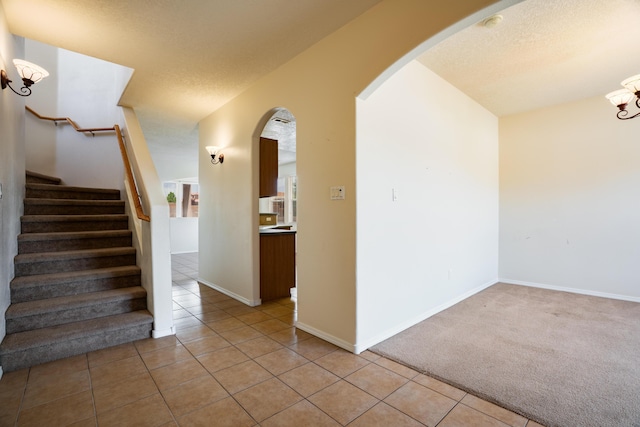 5485 Roosevelt Loop NE, Rio Rancho, NM 87144 - unfurnished room featuring arched walkways, a chandelier, light tile patterned floors, stairway, and a textured ceiling