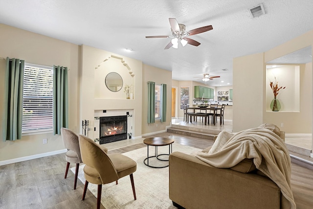 4432 La Paloma Rd NW, Albuquerque, NM 87120 - living area featuring light wood-style flooring, ceiling fan, a glass covered fireplace, and a textured ceiling
