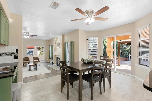 4432 La Paloma Rd NW, Albuquerque, NM 87120 - dining room with ceiling fan, a textured ceiling, a fireplace, and light tile patterned floors