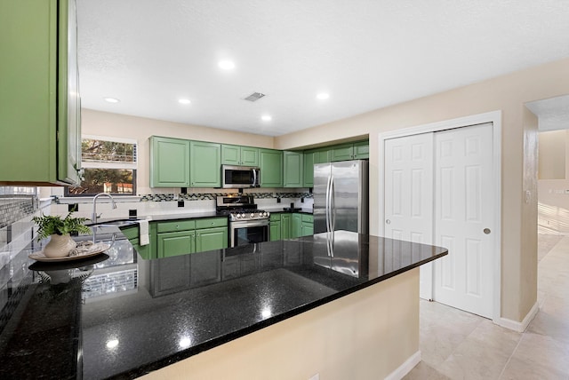 4432 La Paloma Rd NW, Albuquerque, NM 87120 - kitchen featuring appliances with stainless steel finishes, green cabinets, a peninsula, backsplash, and dark stone countertops