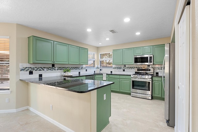 4432 La Paloma Rd NW, Albuquerque, NM 87120 - kitchen with stainless steel appliances, green cabinetry, a peninsula, tasteful backsplash, and recessed lighting