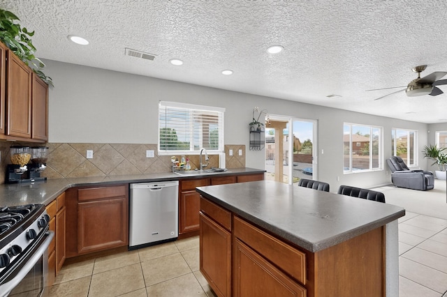 1191 Carrizo St NW, Los Lunas, NM 87031 - kitchen featuring appliances with stainless steel finishes, dark countertops, open floor plan, healthy amount of natural light, and a textured ceiling