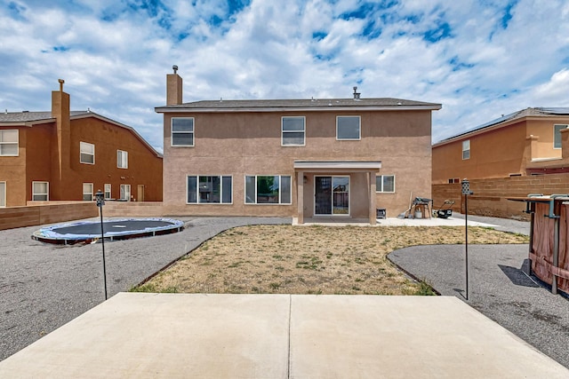 1191 Carrizo St NW, Los Lunas, NM 87031 - rear view of property with a trampoline, a patio area, stucco siding, and a chimney