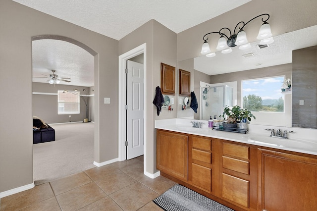 1191 Carrizo St NW, Los Lunas, NM 87031 - full bathroom featuring a textured ceiling, tile patterned flooring, ceiling fan, double vanity, and a stall shower