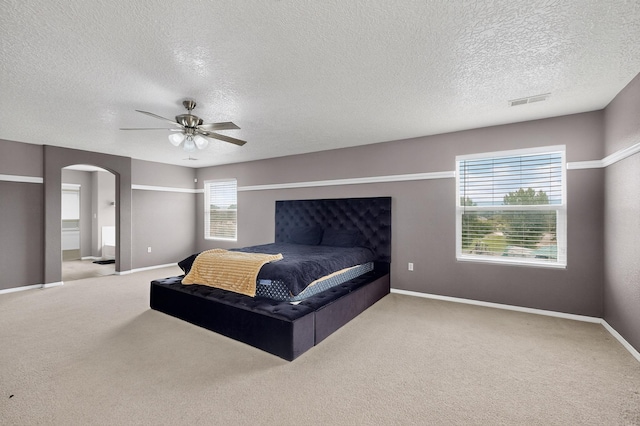 1191 Carrizo St NW, Los Lunas, NM 87031 - carpeted bedroom featuring arched walkways, a textured ceiling, a ceiling fan, and connected bathroom