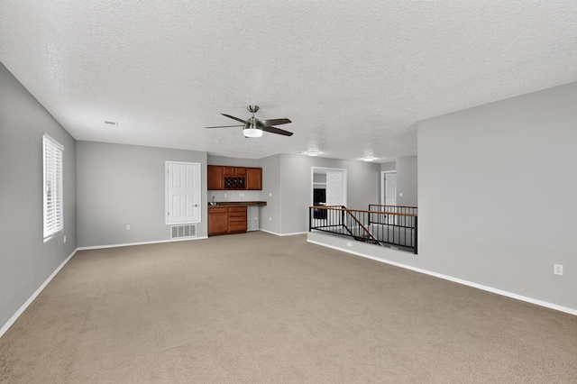 1191 Carrizo St NW, Los Lunas, NM 87031 - unfurnished living room with light carpet, ceiling fan, and a textured ceiling