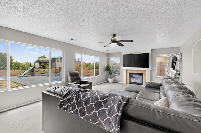 1191 Carrizo St NW, Los Lunas, NM 87031 - living room with carpet, a ceiling fan, a fireplace, and a textured ceiling