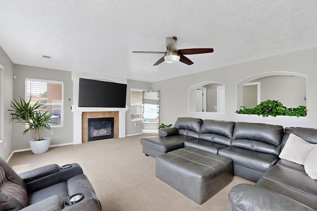 1191 Carrizo St NW, Los Lunas, NM 87031 - living room featuring a ceiling fan, a tiled fireplace, a textured ceiling, and carpet floors