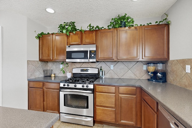 1191 Carrizo St NW, Los Lunas, NM 87031 - kitchen featuring appliances with stainless steel finishes, brown cabinetry, and a textured ceiling