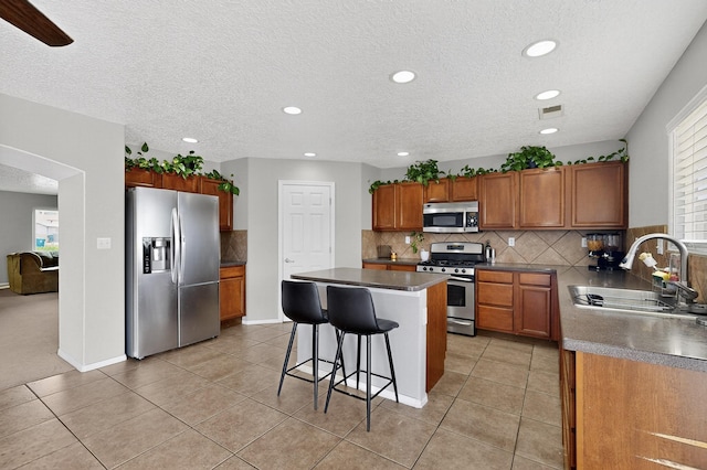 1191 Carrizo St NW, Los Lunas, NM 87031 - kitchen featuring appliances with stainless steel finishes, a kitchen island, tasteful backsplash, a breakfast bar area, and recessed lighting