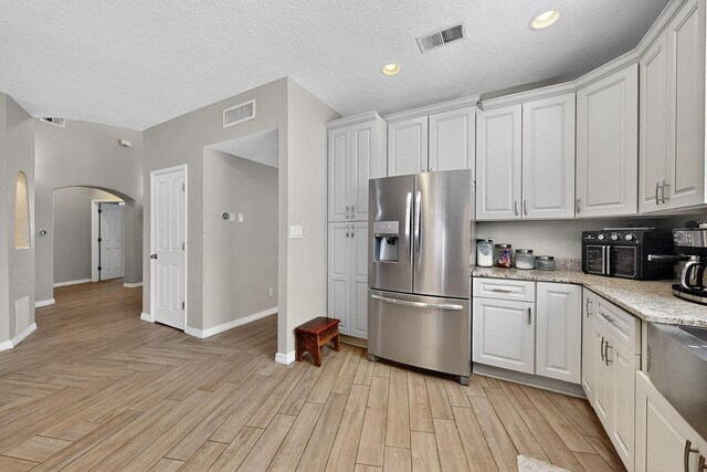 3546 Newcastle Dr SE, Rio Rancho, NM 87124 - kitchen featuring stainless steel fridge with ice dispenser, white cabinets, arched walkways, light wood-style floors, and recessed lighting