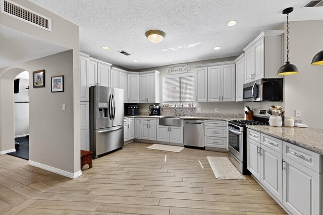 3546 Newcastle Dr SE, Rio Rancho, NM 87124 - kitchen with stainless steel appliances, arched walkways, light wood finished floors, decorative light fixtures, and recessed lighting