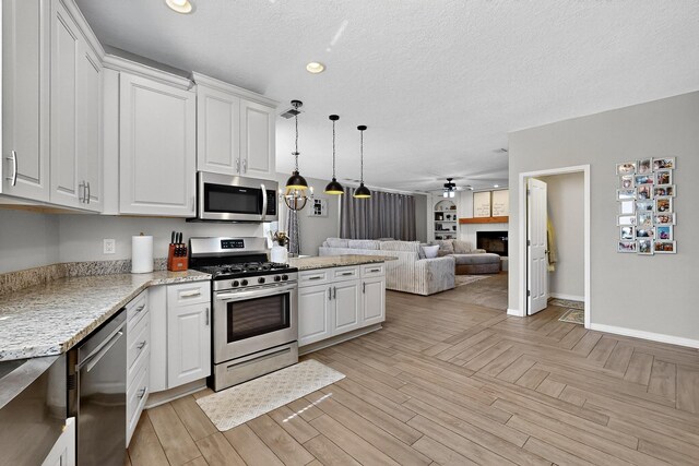 3546 Newcastle Dr SE, Rio Rancho, NM 87124 - kitchen with appliances with stainless steel finishes, open floor plan, white cabinets, a tile fireplace, and recessed lighting