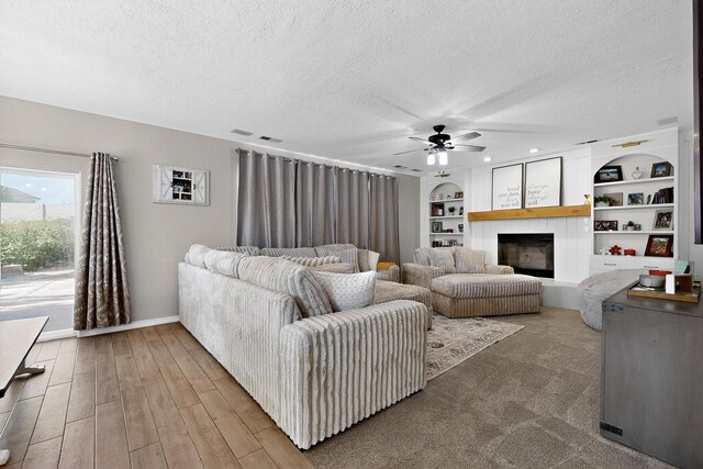 3546 Newcastle Dr SE, Rio Rancho, NM 87124 - living area featuring a textured ceiling, a fireplace, a ceiling fan, built in shelves, and wood finished floors