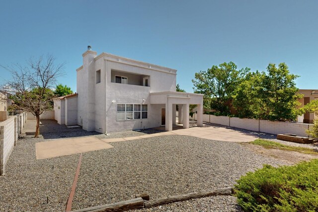 3546 Newcastle Dr SE, Rio Rancho, NM 87124 - back of property with stucco siding, a patio, a fenced backyard, and a chimney