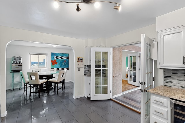 1308 Boatright Dr NE, Albuquerque, NM 87112 - dining area featuring french doors, wine cooler, dark tile patterned flooring, and arched walkways