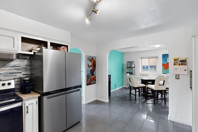 1308 Boatright Dr NE, Albuquerque, NM 87112 - kitchen featuring stainless steel appliances, arched walkways, backsplash, dark tile patterned flooring, and light countertops