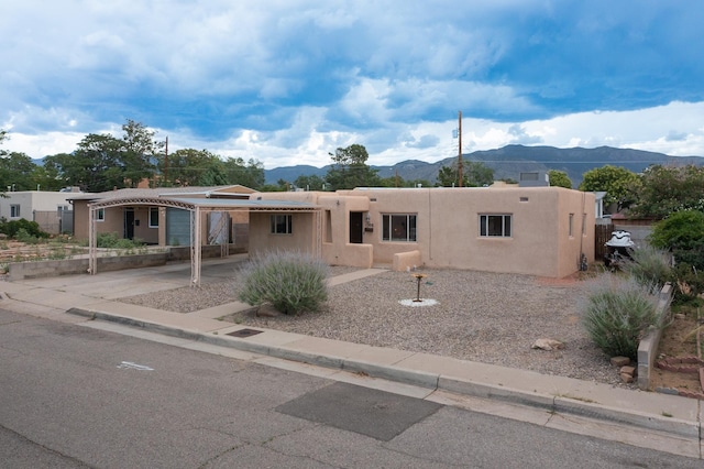 1308 Boatright Dr NE, Albuquerque, NM 87112 - pueblo-style home with a mountain view, stucco siding, a carport, and driveway