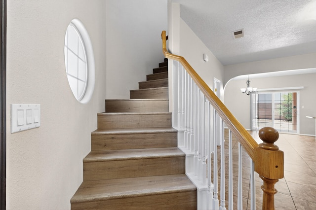 5508 Carefree Ave NW, Albuquerque, NM 87120 - stairs featuring a chandelier, a textured ceiling, and tile patterned floors