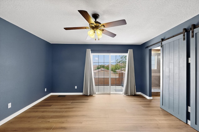5508 Carefree Ave NW, Albuquerque, NM 87120 - spare room featuring ceiling fan, wood finished floors, a textured ceiling, and a barn door
