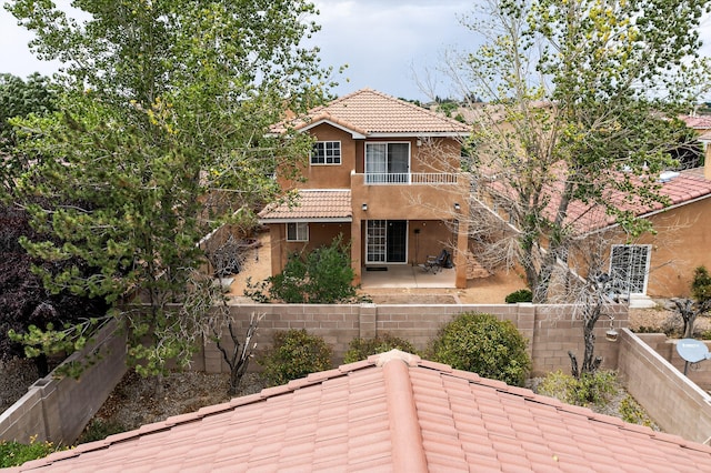 5508 Carefree Ave NW, Albuquerque, NM 87120 - back of house with a balcony, stucco siding, a patio, a tile roof, and a fenced backyard