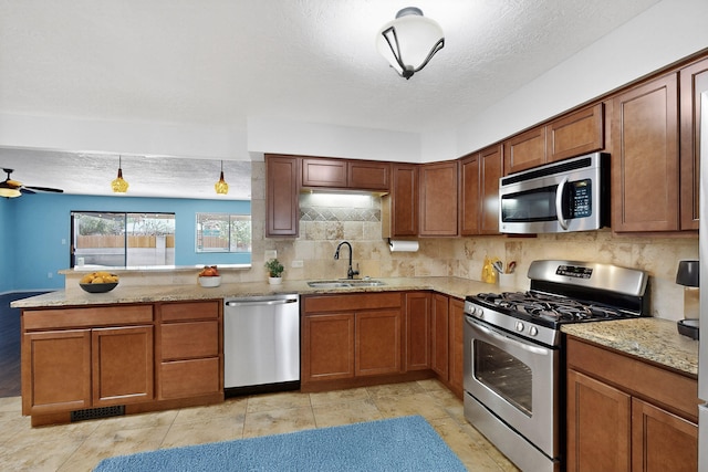 12208 Phoenix Ave NE, Albuquerque, NM 87112 - kitchen featuring stainless steel appliances, a peninsula, backsplash, light stone countertops, and brown cabinetry