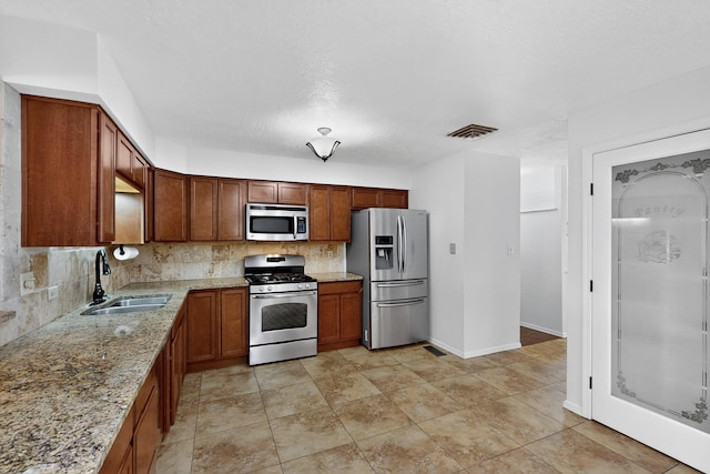12208 Phoenix Ave NE, Albuquerque, NM 87112 - kitchen with stainless steel appliances, decorative backsplash, light stone countertops, and brown cabinets