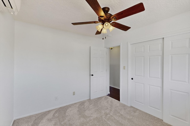 12208 Phoenix Ave NE, Albuquerque, NM 87112 - unfurnished bedroom featuring a wall unit AC, carpet floors, a closet, a textured ceiling, and a ceiling fan