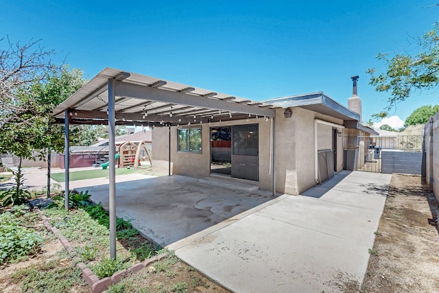 12208 Phoenix Ave NE, Albuquerque, NM 87112 - view of side of home with stucco siding, a patio, a gate, and a chimney