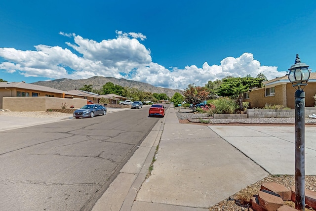 12208 Phoenix Ave NE, Albuquerque, NM 87112 - view of asphalt road featuring sidewalks, a mountain view, curbs, and a residential view