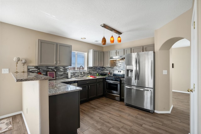 5478 Salem Ct NE, Rio Rancho, NM 87144 - kitchen featuring appliances with stainless steel finishes, a peninsula, under cabinet range hood, light stone counters, and gray cabinets