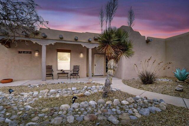 39 Pine Rd, Placitas, NM 87043 - exterior entry at dusk featuring a patio and stucco siding