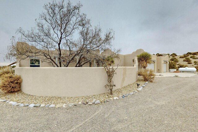 39 Pine Rd, Placitas, NM 87043 - view of side of home featuring a fenced front yard, stucco siding, and gravel driveway