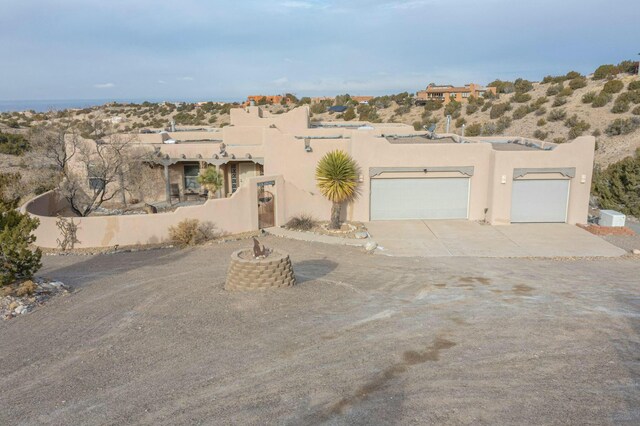 39 Pine Rd, Placitas, NM 87043 - pueblo-style house with stucco siding, an attached garage, and concrete driveway