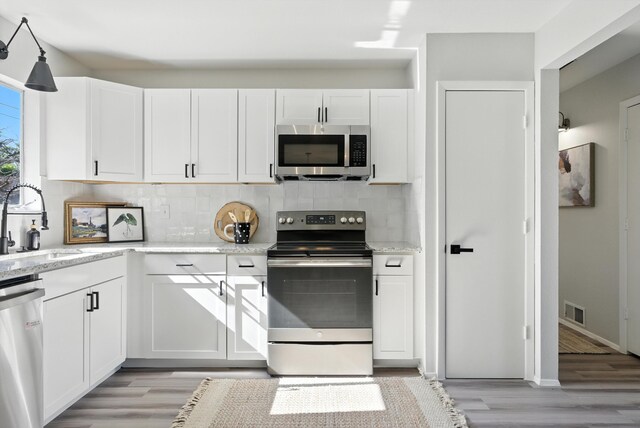 11517 San Jacinto Ave NE, Albuquerque, NM 87112 - kitchen featuring stainless steel appliances, light wood-style flooring, and tasteful backsplash