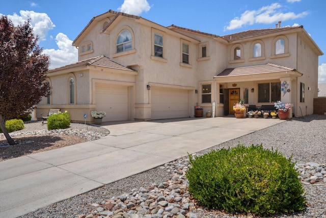 1417 Montiano Loop SE, Rio Rancho, NM 87124 - mediterranean / spanish-style house with an attached garage, a tile roof, stucco siding, and driveway