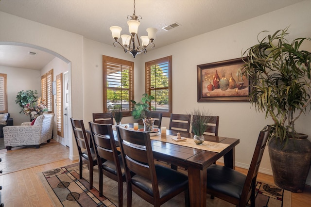 1417 Montiano Loop SE, Rio Rancho, NM 87124 - dining space with arched walkways, light wood-style floors, and a chandelier
