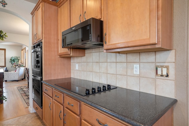 1417 Montiano Loop SE, Rio Rancho, NM 87124 - kitchen featuring black appliances, arched walkways, decorative backsplash, dark stone counters, and light wood finished floors