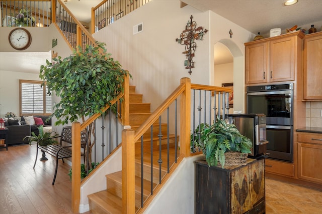1417 Montiano Loop SE, Rio Rancho, NM 87124 - stairs with a towering ceiling, arched walkways, recessed lighting, and wood finished floors