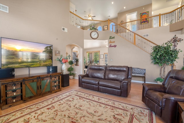 1417 Montiano Loop SE, Rio Rancho, NM 87124 - living area featuring a high ceiling, wood finished floors, arched walkways, a ceiling fan, and stairs