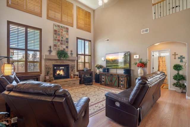 1417 Montiano Loop SE, Rio Rancho, NM 87124 - living area featuring a high ceiling, wood finished floors, a stone fireplace, ceiling fan, and arched walkways