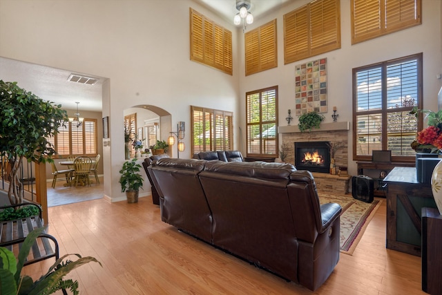 1417 Montiano Loop SE, Rio Rancho, NM 87124 - living room with a high ceiling, light wood-style floors, a stone fireplace, and plenty of natural light