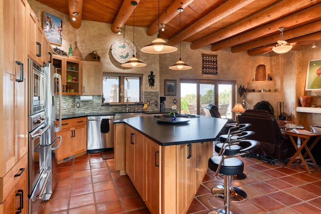 15 Sunset Blvd, Placitas, NM 87043 - kitchen featuring appliances with stainless steel finishes, a wooden ceiling with exposed beams, dark countertops, a breakfast bar area, and tile patterned flooring