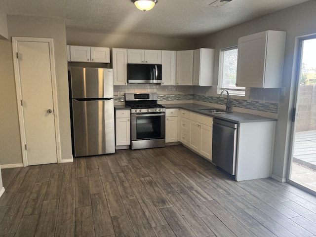 3005 Quail Point Dr, Albuquerque, NM 87120 - kitchen with appliances with stainless steel finishes, dark wood-type flooring, white cabinets, tasteful backsplash, and healthy amount of natural light