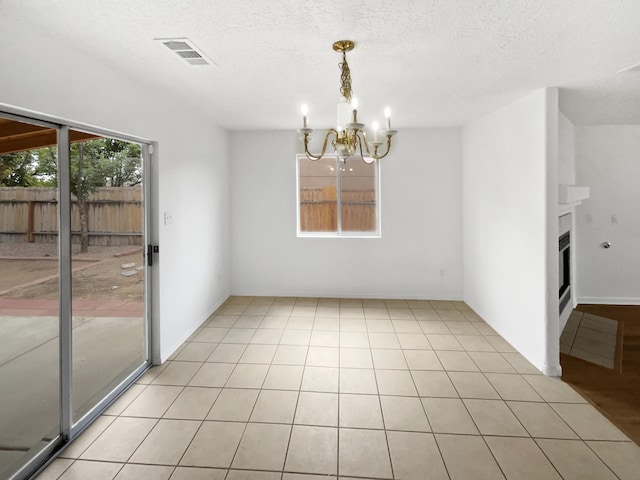 5355 Feather Rock Pl NW, Albuquerque, NM 87114 - empty room featuring a chandelier, a textured ceiling, and a fireplace