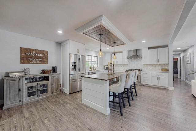 4320 Blumenshine Cir SW, Albuquerque, NM 87105 - kitchen featuring appliances with stainless steel finishes, wall chimney range hood, light wood-style floors, backsplash, and a center island