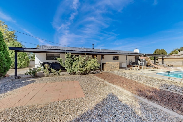 4320 Blumenshine Cir SW, Albuquerque, NM 87105 - rear view of house with a patio, stucco siding, an outdoor pool, and a metal roof