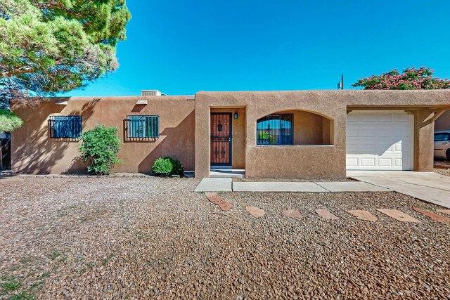 10409 Britt Ct NE, Albuquerque, NM 87112 - pueblo revival-style home featuring stucco siding, an attached garage, and driveway