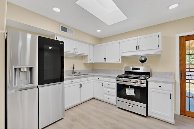10409 Britt Ct NE, Albuquerque, NM 87112 - kitchen featuring appliances with stainless steel finishes, a skylight, light wood-type flooring, white cabinetry, and recessed lighting