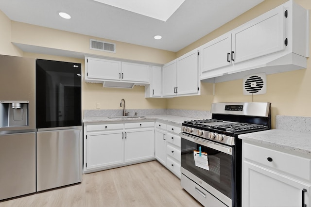 10409 Britt Ct NE, Albuquerque, NM 87112 - kitchen featuring appliances with stainless steel finishes, light wood-style flooring, white cabinetry, light stone counters, and recessed lighting